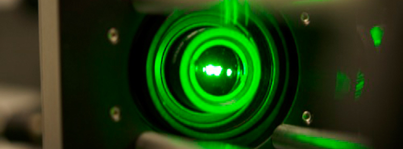 zur Vergrößerungsansicht des Bildes: Durchgang von grünem Laserlicht durch eine optische Linse