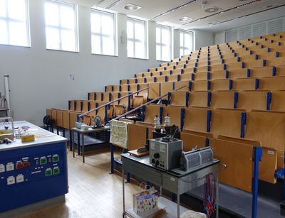 Hörsaal mit nach oben ansteigenden Sitzplätzen, im Vordergrund sind ein paar Experimentiergeräte zu sehen, kleiner Hörsaal der Physik, Universität Leipzig, Foto: Kilian Peisker