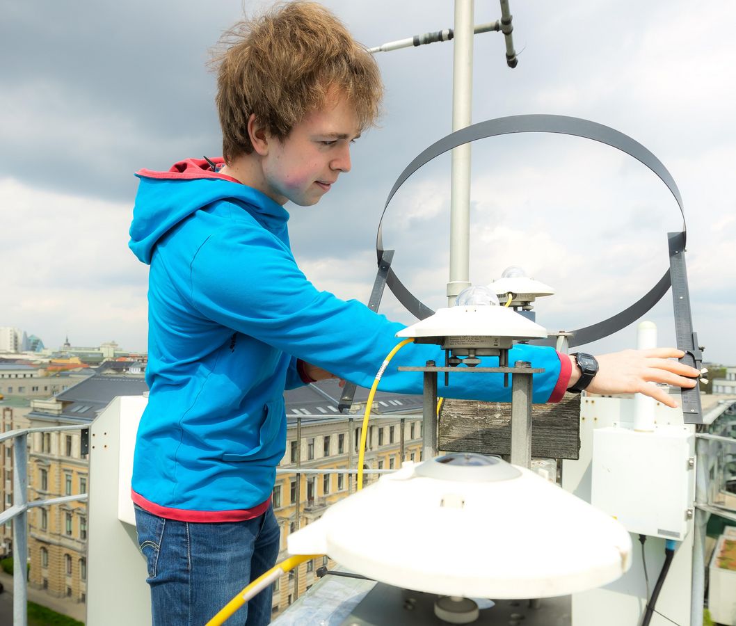 Ein junger Mann steht auf dem Turm des Instituts für Meteorologie und liest Wetterdaten ab. Foto: Swen Reichhold