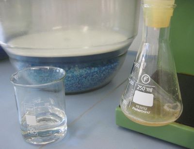 Nahaufnahme eines Becherglases mit Salzsäure und eines Erlenmeyerkolbens mit Sediment im Labor, Foto: Institut für Geographie