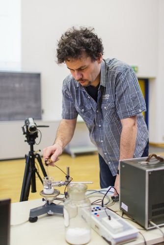 Lecturer standing bent over an experimental setup