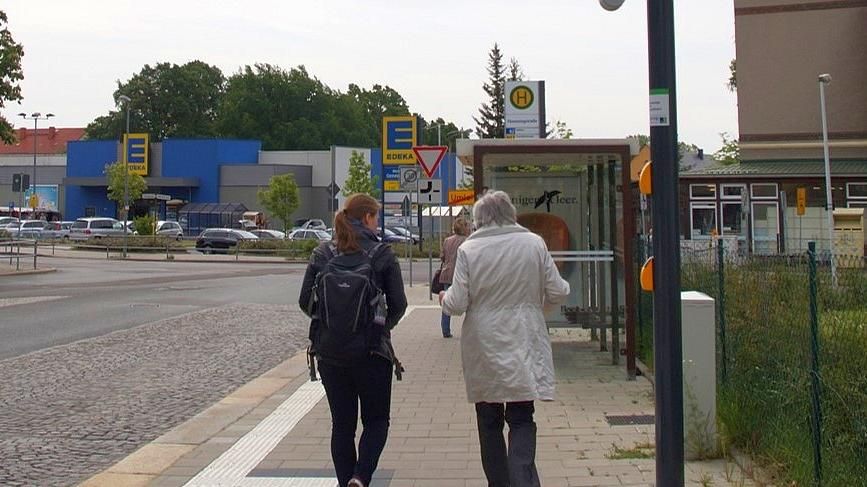 Eine junge und eine ältere Frau gehen nebeneinander auf dem Fußweg und unterhalten sich.