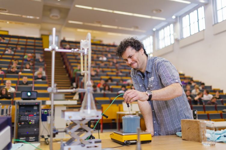 Lecturer stands in front of students in the lecture theatre and prepares equipment