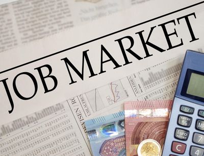 Ein Taschenrechner und zwei Euro-Scheine liegen auf der Zeitung mit dem Titel Job Market. Foto: Colourbox