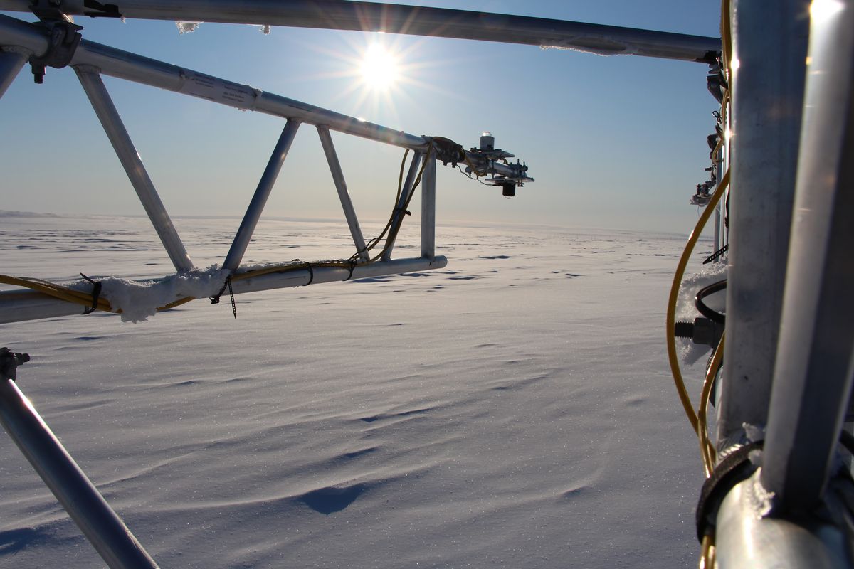 Ein Messsystem mit Strahlungssensoren steht in der schneebedeckten, ebenen Landschaft in Nordgrönland. Foto: Tobias Donth