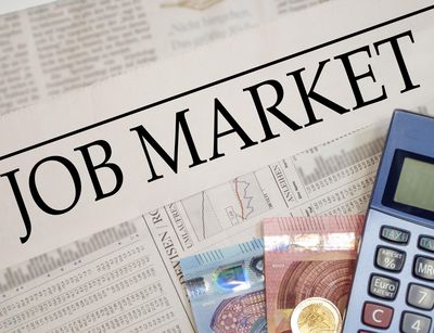 Ein Taschenrechner und zwei Euro-Scheine liegen auf der Zeitung mit dem Titel Job Market. Foto: Colourbox