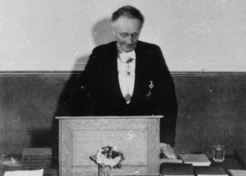 zur Vergrößerungsansicht des Bildes: Vilhelm Bjerknes stehend hinter dem Podium bei der Festansprache anlässlich des 25-jährigen Bestehens des Geophysikalischen Instituts im Jahr 1938